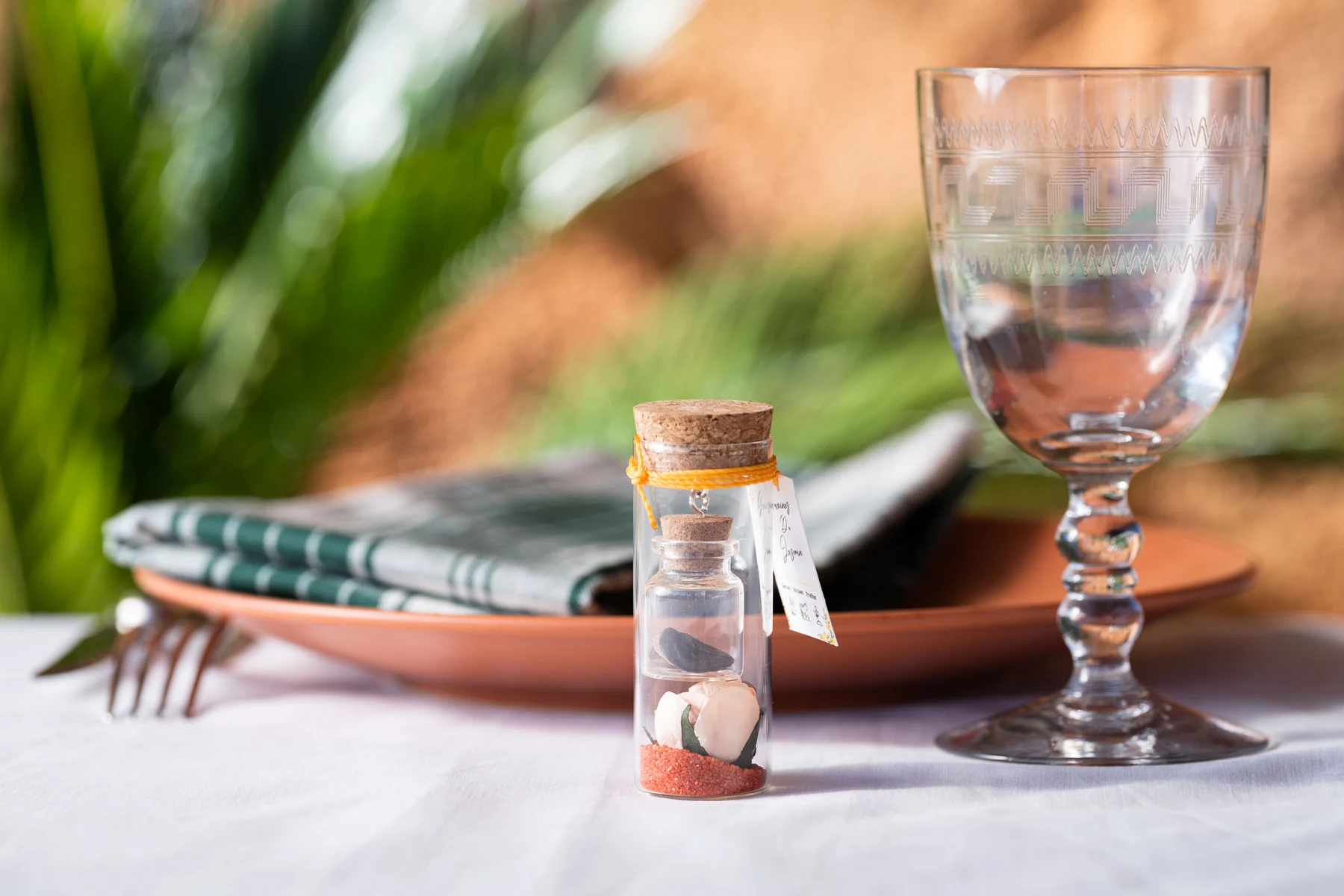 Une fiole de graines personnalisée sur une table de réception, avec une serviette verte et un verre gravé